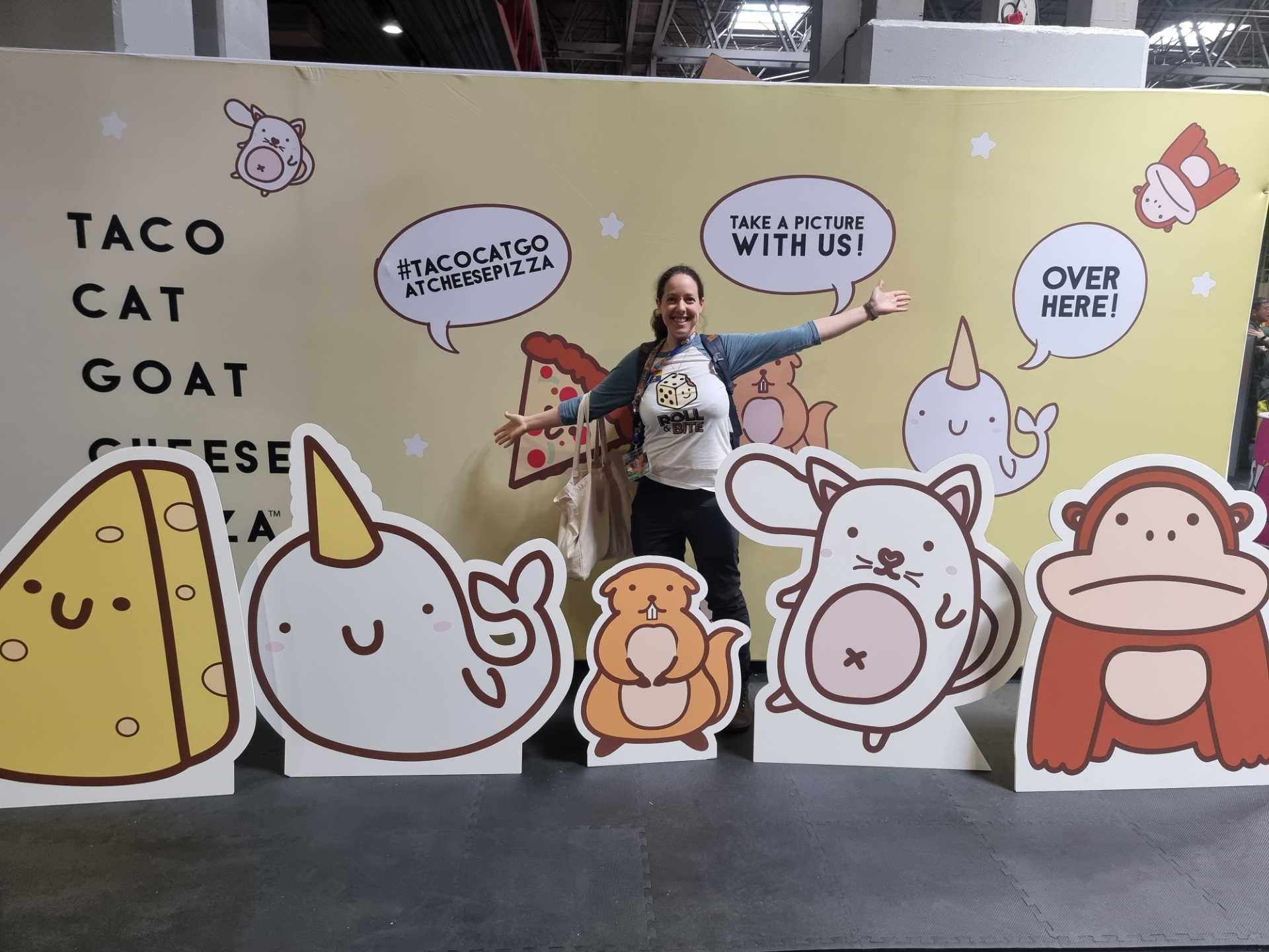 Helen Moore of Roll and Bite standing in front of a Taco Goat Cheese Pizza Banner